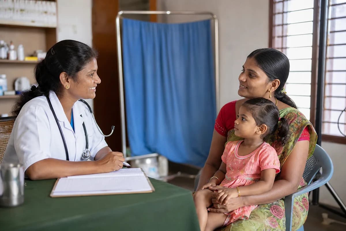 A clinician speaking calmly with a mother and child in a welcoming clinic.